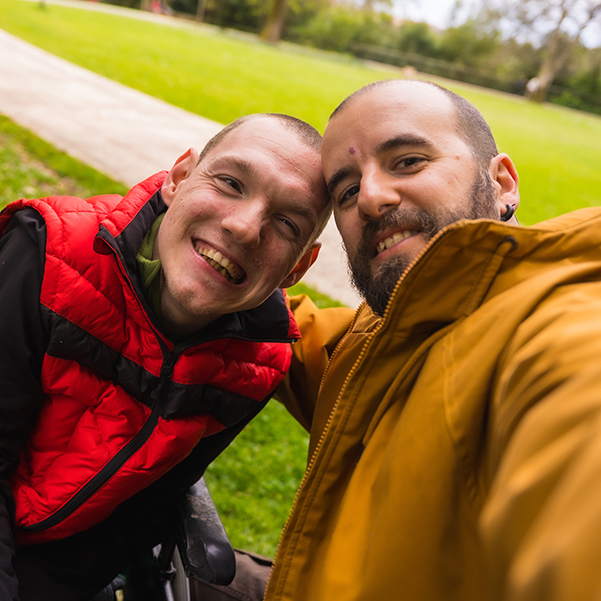 Carer and man with disability taking a smiling portrait