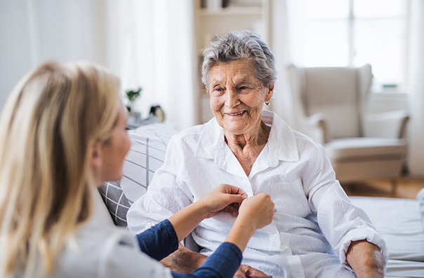 Young women helping button shirt for elderly woman