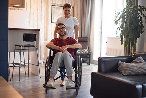 Care worker pushing man in wheelchair through house