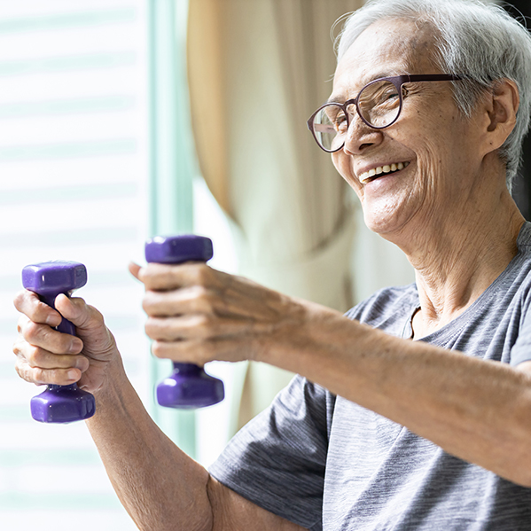 Happy elderly man exercising with purple dumbbells at home, promoting fitness and health.