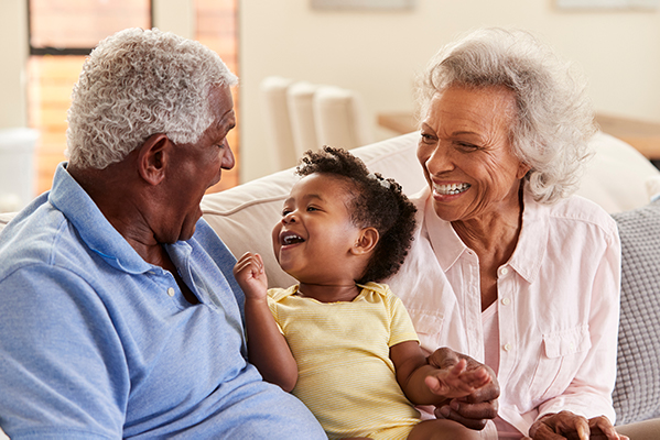 Grandparents sitting on sofa spending time with grandchild