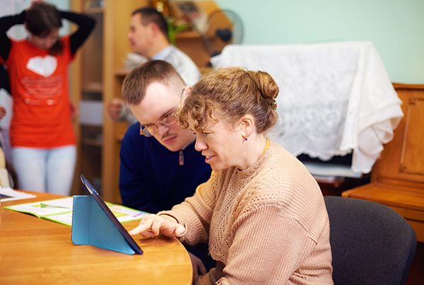 Two friends with disabilities using a tablet at home