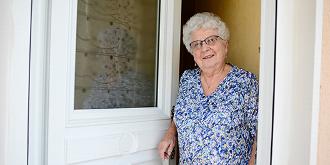 Smiling elderly woman opening front door 