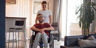 Smiling woman assisted man with disability and pushing his wheelchair